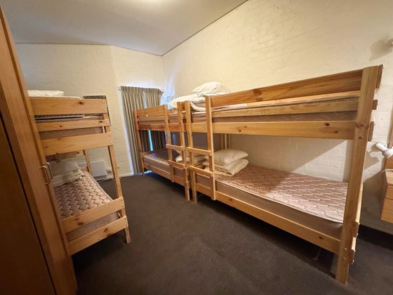 Room 9, the Bunkroom: three timber bunk units giving six single berths, with a wardrobe and a curtained window.